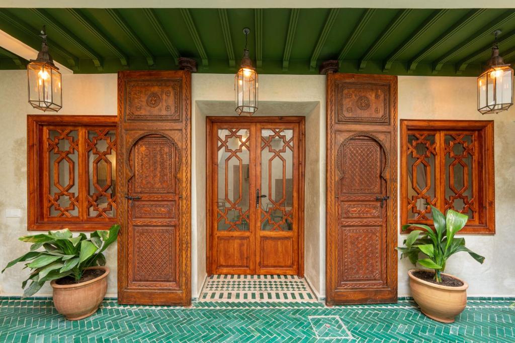 a house with two wooden doors and two potted plants at Riad Senja in Marrakesh
