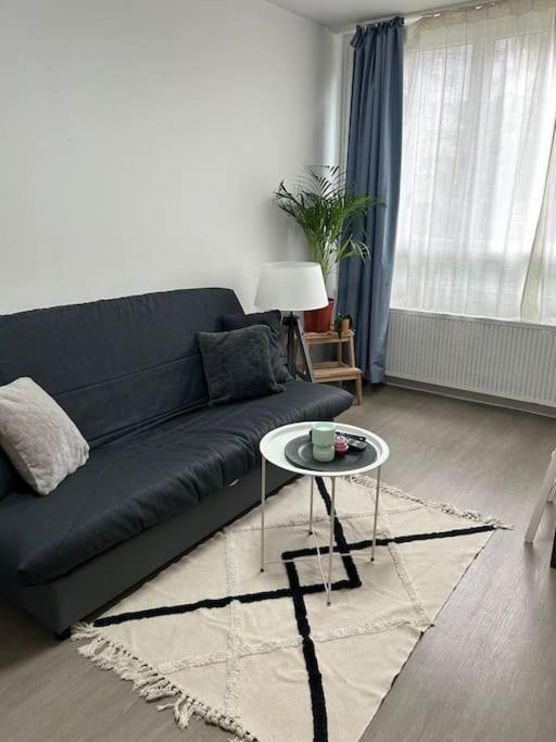 un salon avec un canapé bleu et une table dans l'établissement Authentique Paris Aubervilliers, à Aubervilliers