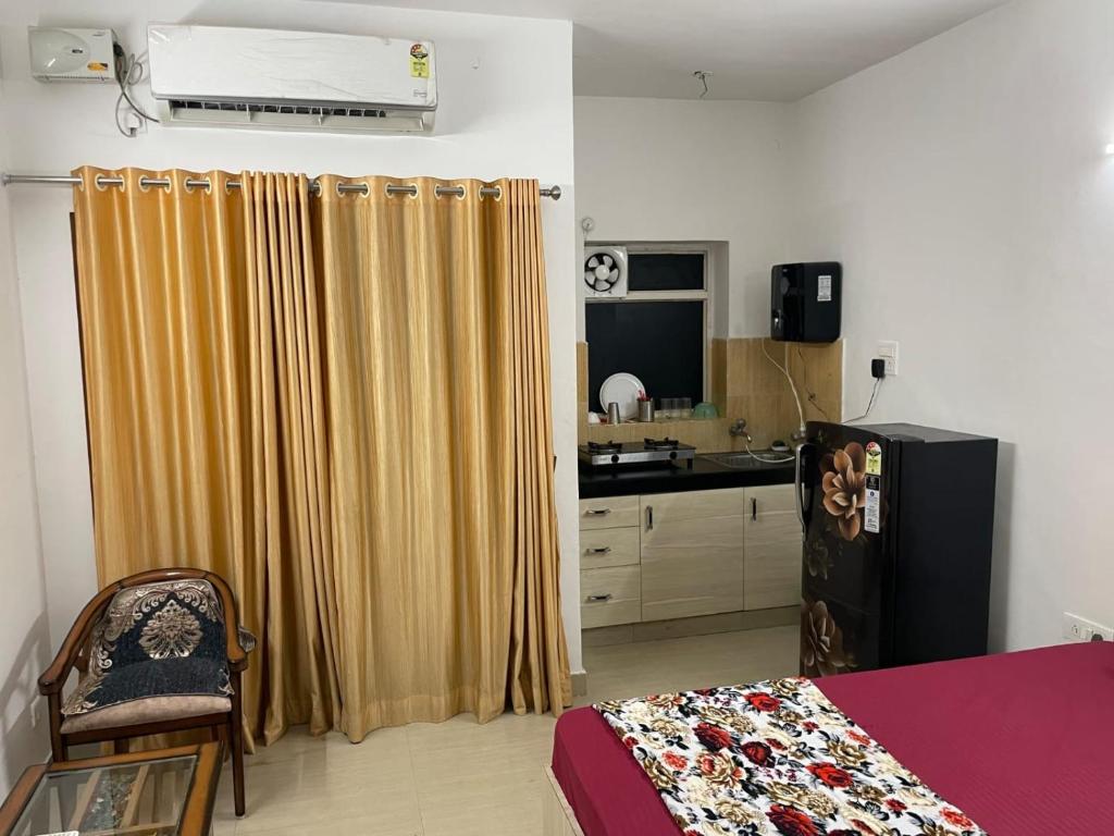 a room with a bed and a refrigerator and a kitchen at VisitorStayInn in Vrindāvan