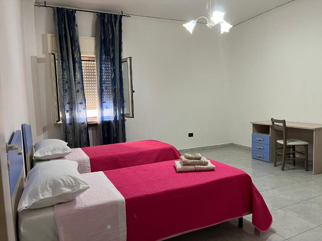 a bedroom with two beds with red and white sheets at Spazioso appartamento - Casa Fe in Rossano Stazione