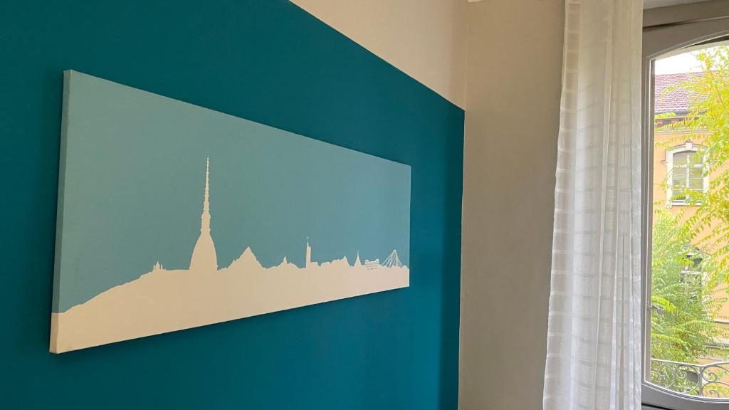a blue wall with a framed picture of a city at Casa Dante in Turin