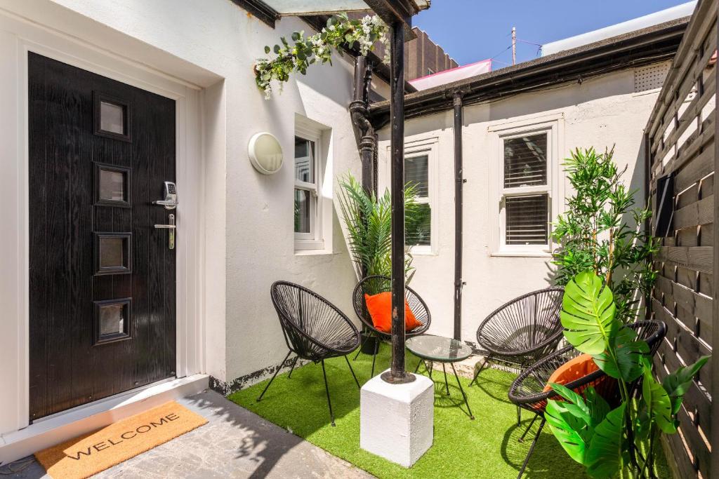 a patio with chairs and a table in front of a door at Seabreeze Hideaway By Kozmo - Cozy 2-Bed Bungalow in Brighton near the Beach With Free WiFi & Terrace by Kozmo Properties in Brighton & Hove