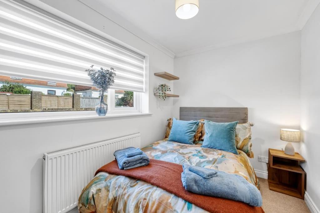 a bedroom with a bed with blue pillows and a window at Minutes from the port of Dover, free WiFi, free offroad private parking and rated a guest favourite on Air b nb! in Kent