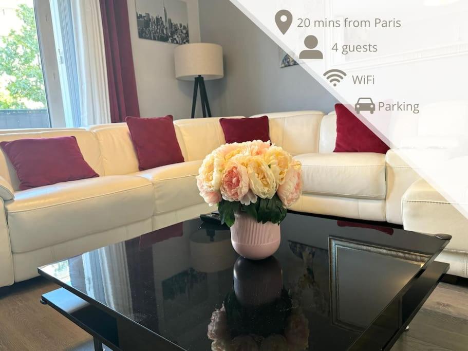 a living room with a couch and a vase of flowers on a table at Appartement confort avec balcon - Champigny in Champigny-sur-Marne