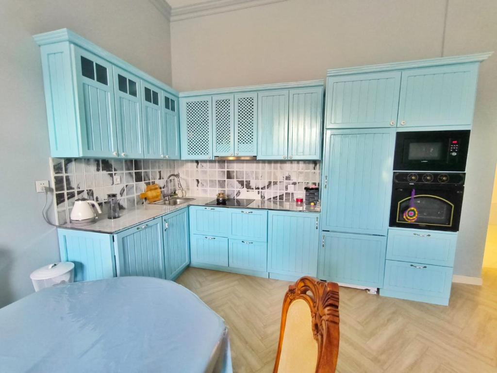 a blue kitchen with blue cabinets and a table at Green City Baku - cozy seaside apartment in Baku