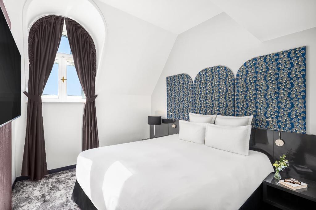 a bedroom with a white bed and a window at Nemzeti Hotel Budapest - MGallery Collection in Budapest
