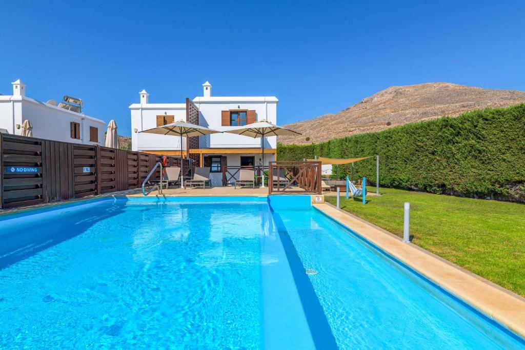 a villa with a swimming pool in front of a house at Lindos Topaz in Lindos