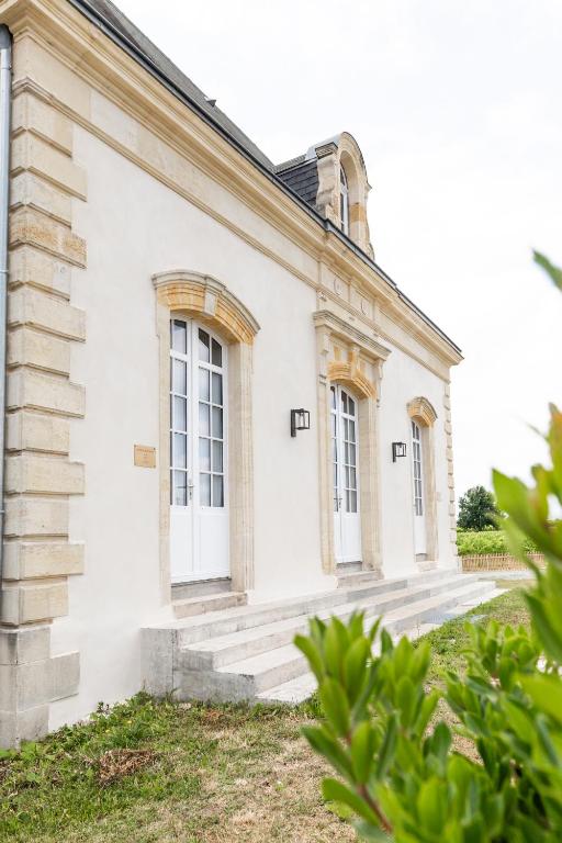 Cette ancienne maison blanche est dotée d'escaliers et de fenêtres. dans l'établissement Château Martinho, à Listrac-Médoc