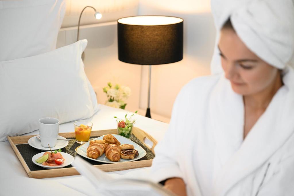 a woman in a hotel room with a tray of food at Nemzeti Hotel Budapest - MGallery Collection in Budapest