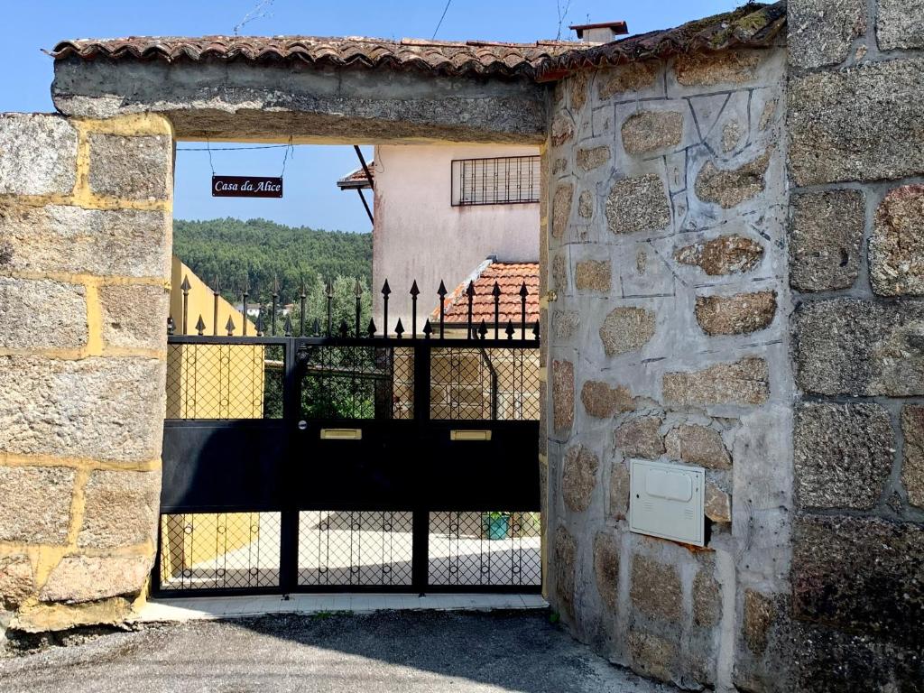 un cancello aperto in un muro di pietra con un edificio di Casa Da Alice a Duas Igrejas