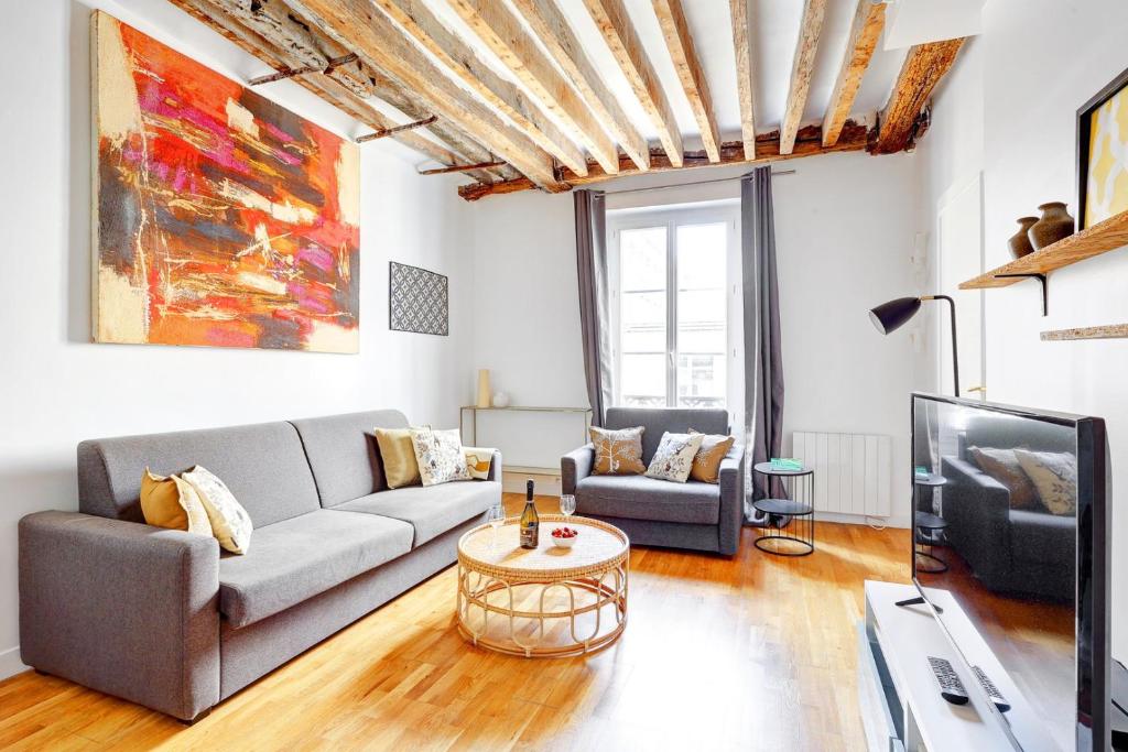 un salon avec un canapé et une télévision dans l'établissement Bluestay 283 - Superbe Appartement dans le Marais, à Paris