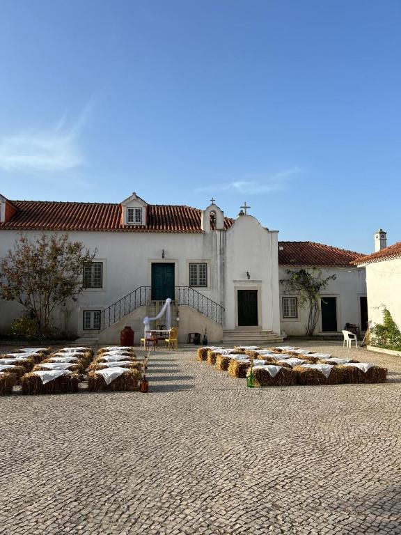 a large white building with bales of hay in a courtyard at Santuário SOS Animal in Casais da Carneiria
