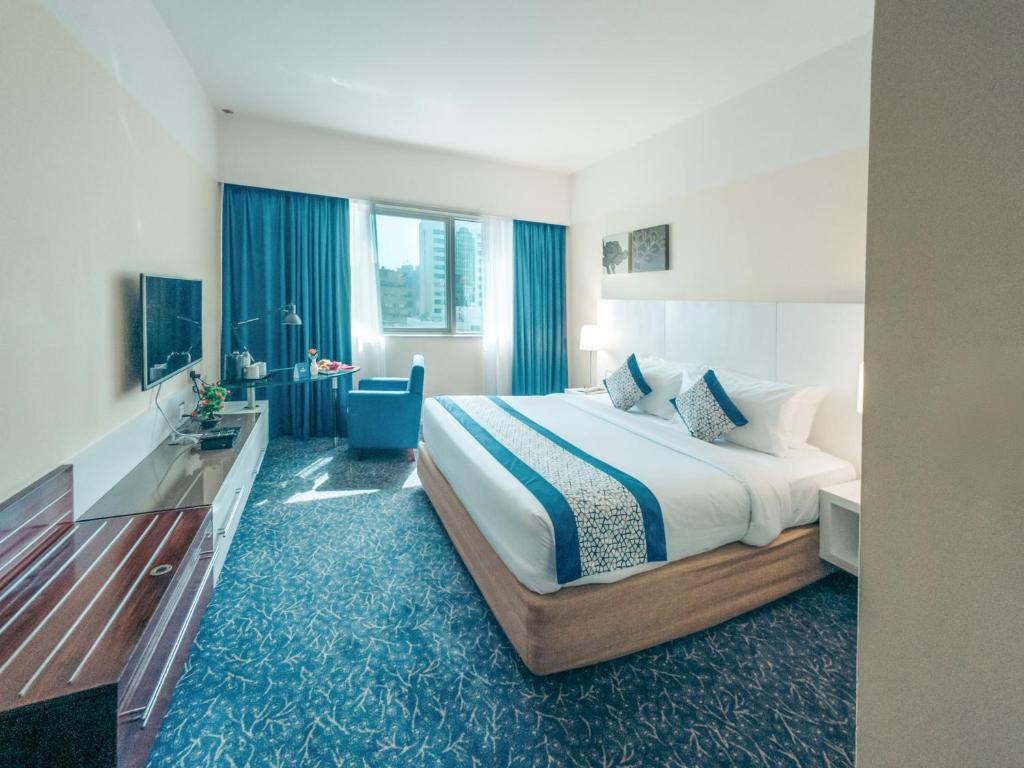 a hotel room with a large bed and a bathroom at Kingsgate Hotel by Millennium in Abu Dhabi