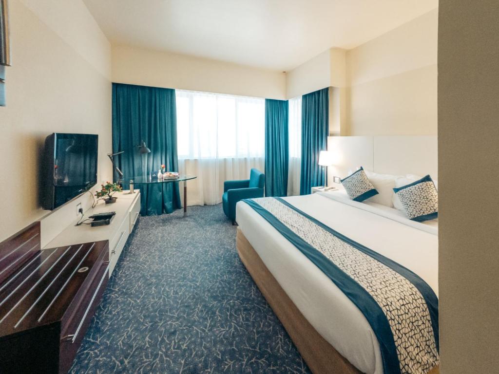 a hotel room with a large bed and a television at Kingsgate Hotel by Millennium in Abu Dhabi