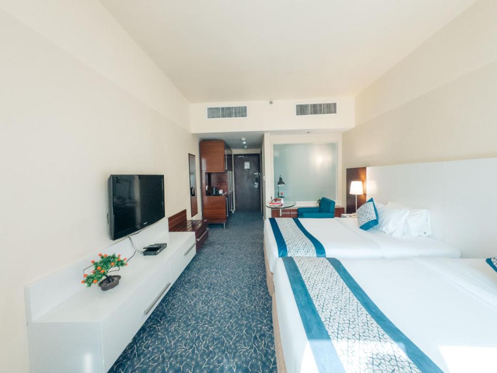 a hotel room with two beds and a flat screen tv at Kingsgate Hotel by Millennium in Abu Dhabi