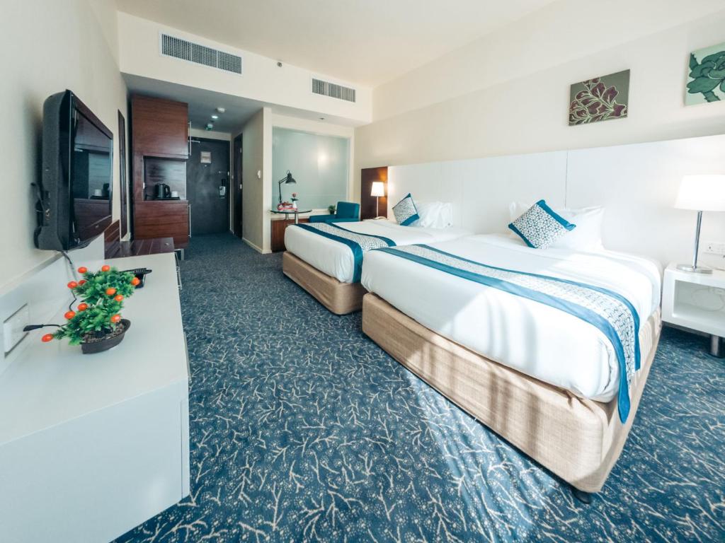 a hotel room with two beds and a television at Kingsgate Hotel by Millennium in Abu Dhabi