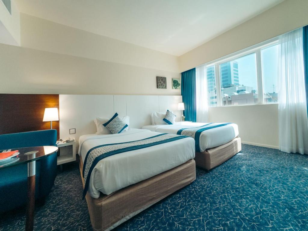 a hotel room with two beds and a window at Kingsgate Hotel by Millennium in Abu Dhabi
