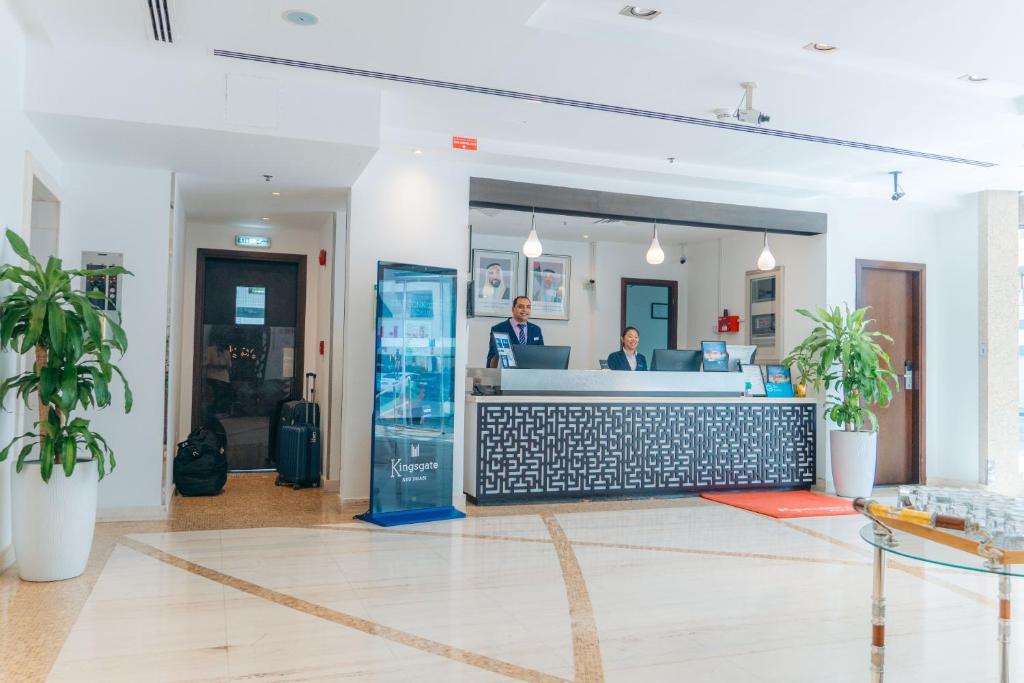 two people standing at a counter in a lobby at Kingsgate Hotel by Millennium in Abu Dhabi
