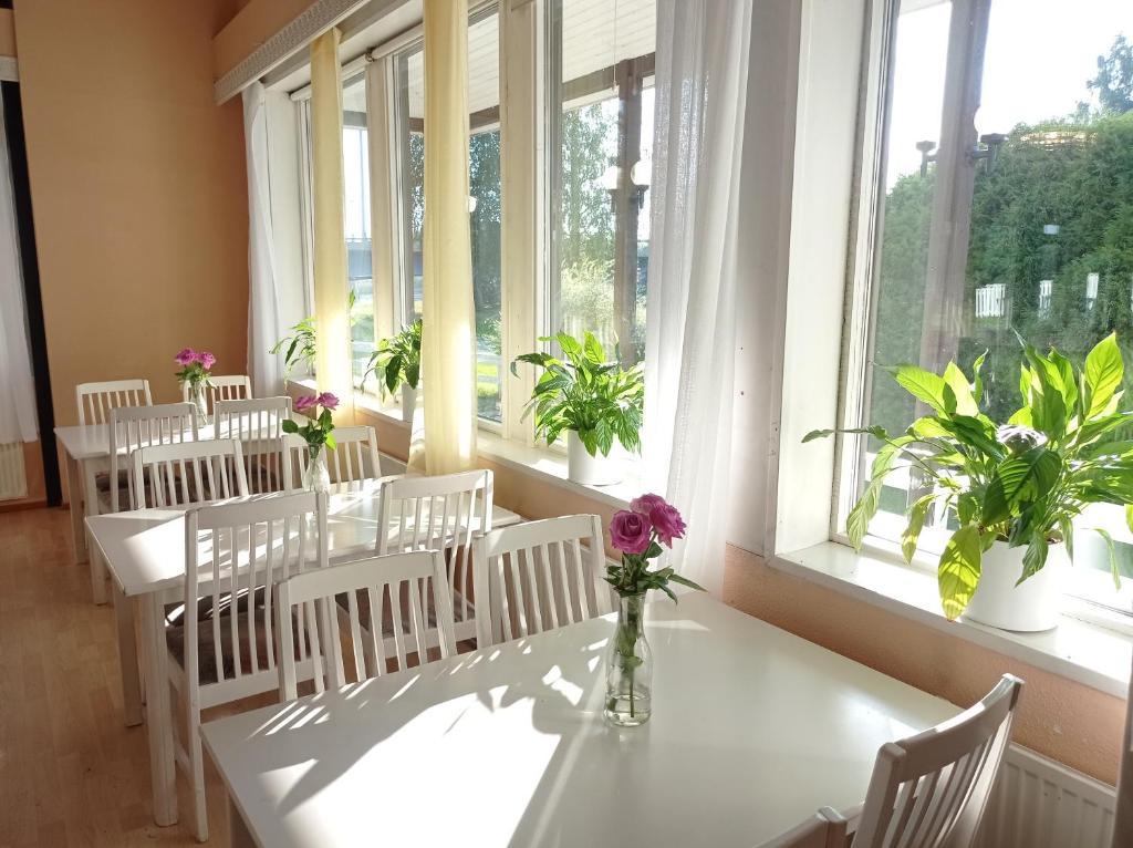 Habitación con mesas blancas, sillas y ventanas blancas. en Rantakartano, en Pori