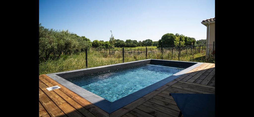 a swimming pool on a wooden deck with a fence at Villa laudun in Laudun