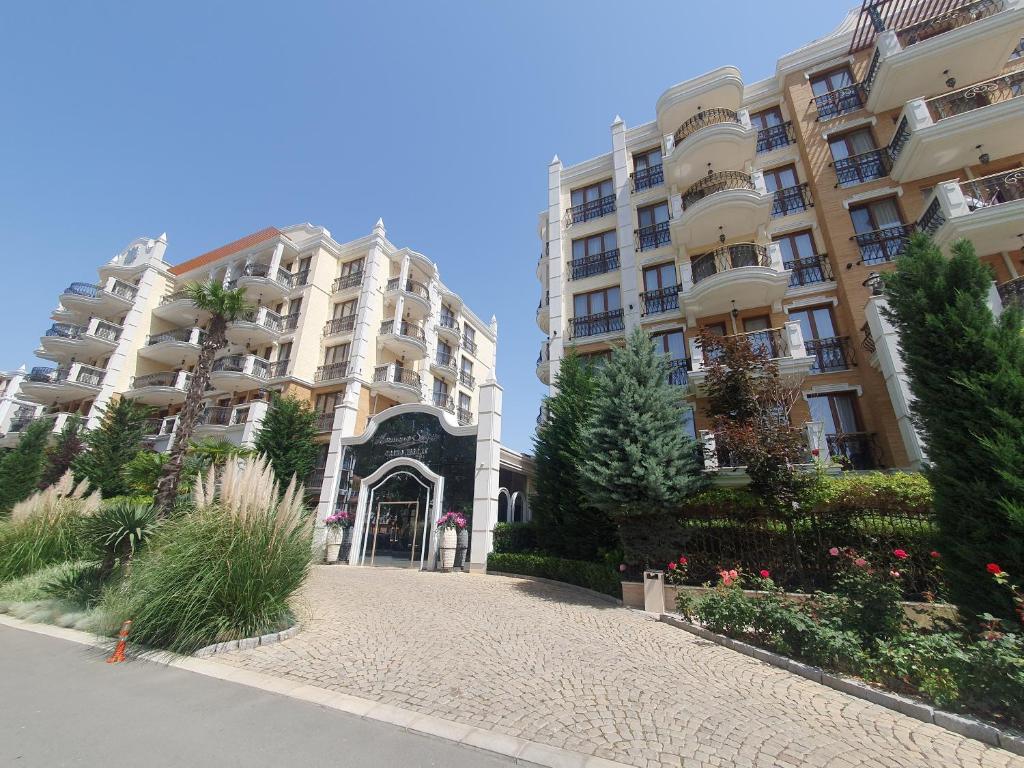 two tall apartment buildings with a walkway in front at Harmony Suites 11 Grand Resort in Sunny Beach