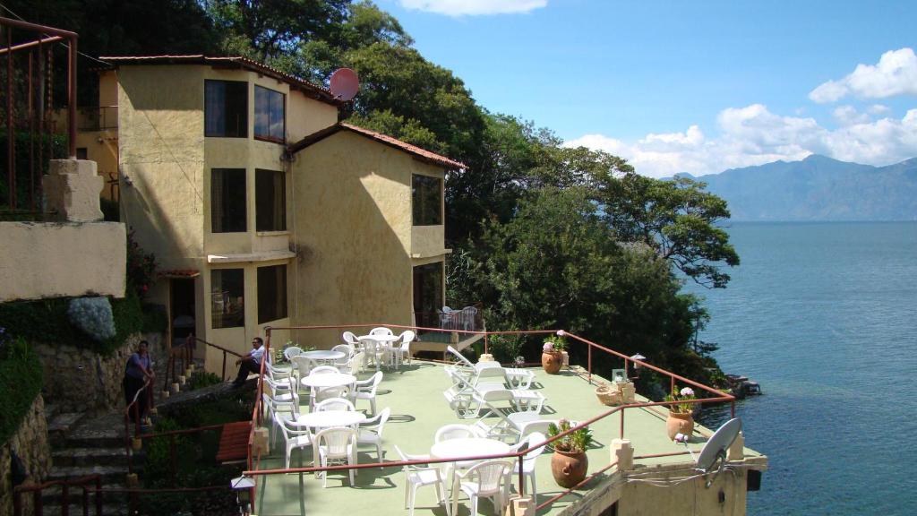 a balcony with tables and chairs on the water at Hotel Restaurante La Villa de los Dioses in San Antonio Palopó