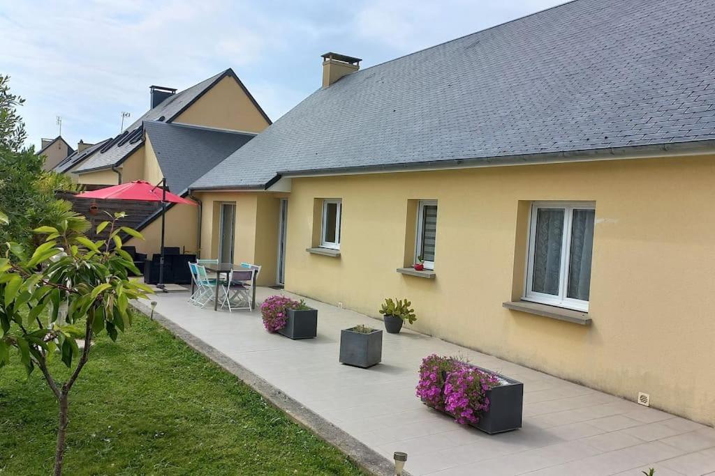 Cette maison jaune dispose d'une terrasse avec des tables et des fleurs. dans l'établissement Chez Denis, maison à la campagne, à Poilley