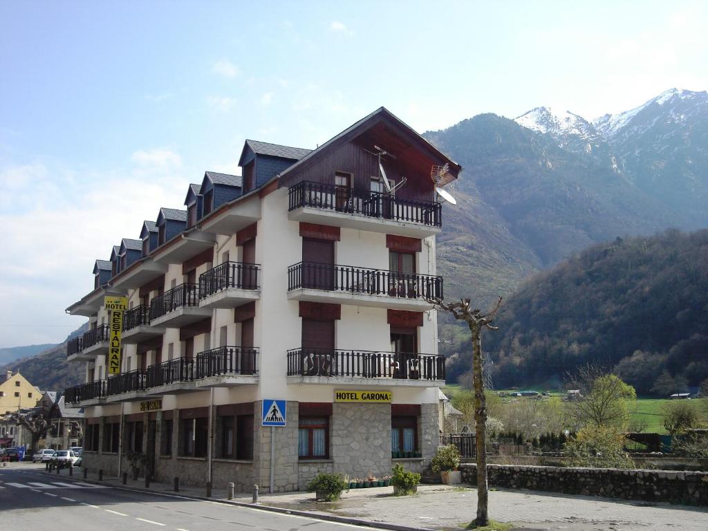 a large building with balconies and mountains in the background at Hotel Garona in Bossost
