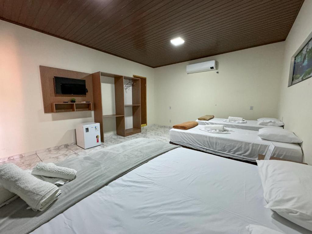 a room with three beds and a tv on the wall at Suítes no centro de Bonito, Bonito Brasil Turismo in Bonito