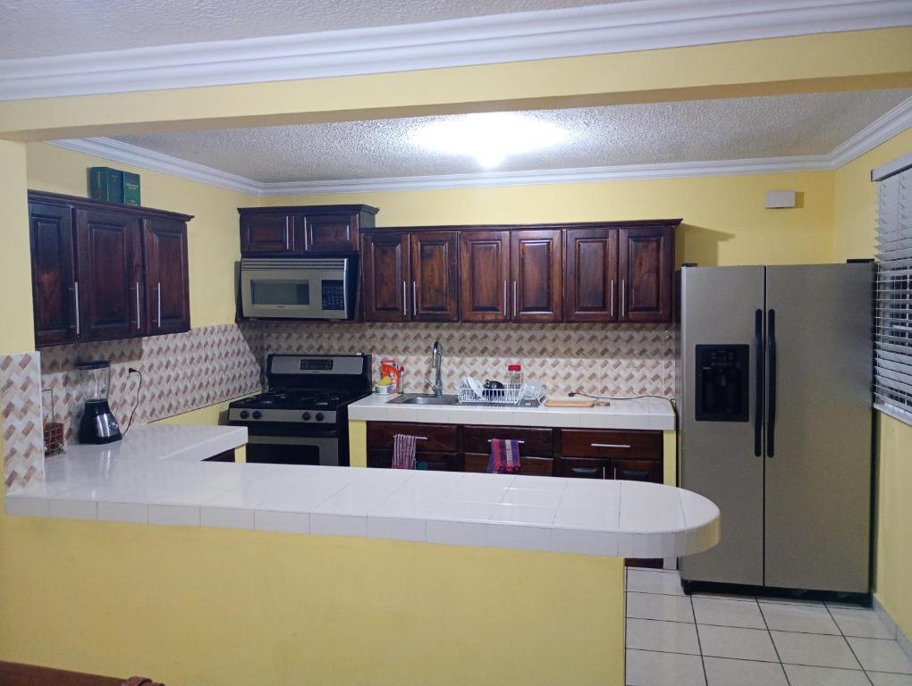 Una cocina con gabinetes de madera y un refrigerador de acero inoxidable. en Santa Ana tu mejor opción, en Santa Ana
