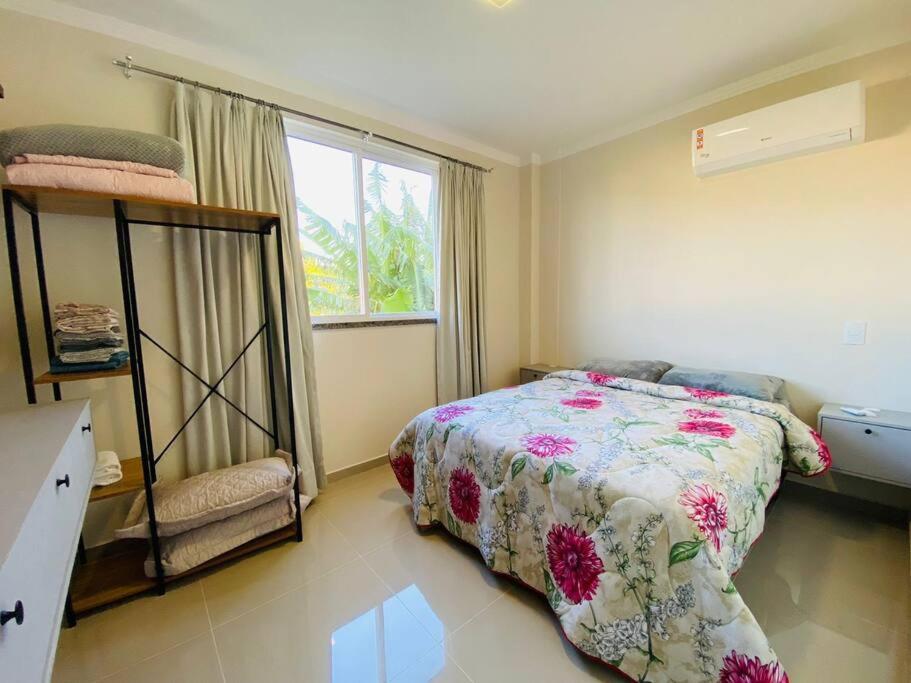 a bedroom with a bed and a window at Apartamento novo - 400m do mar Bombinhas in Bombinhas