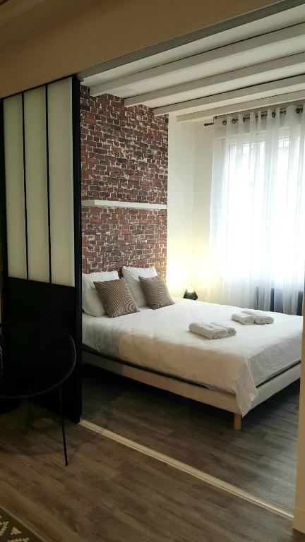 une chambre avec un lit et un mur de briques dans l'établissement Le RUBIS - 2 Chambres - Centre ville, à Amiens
