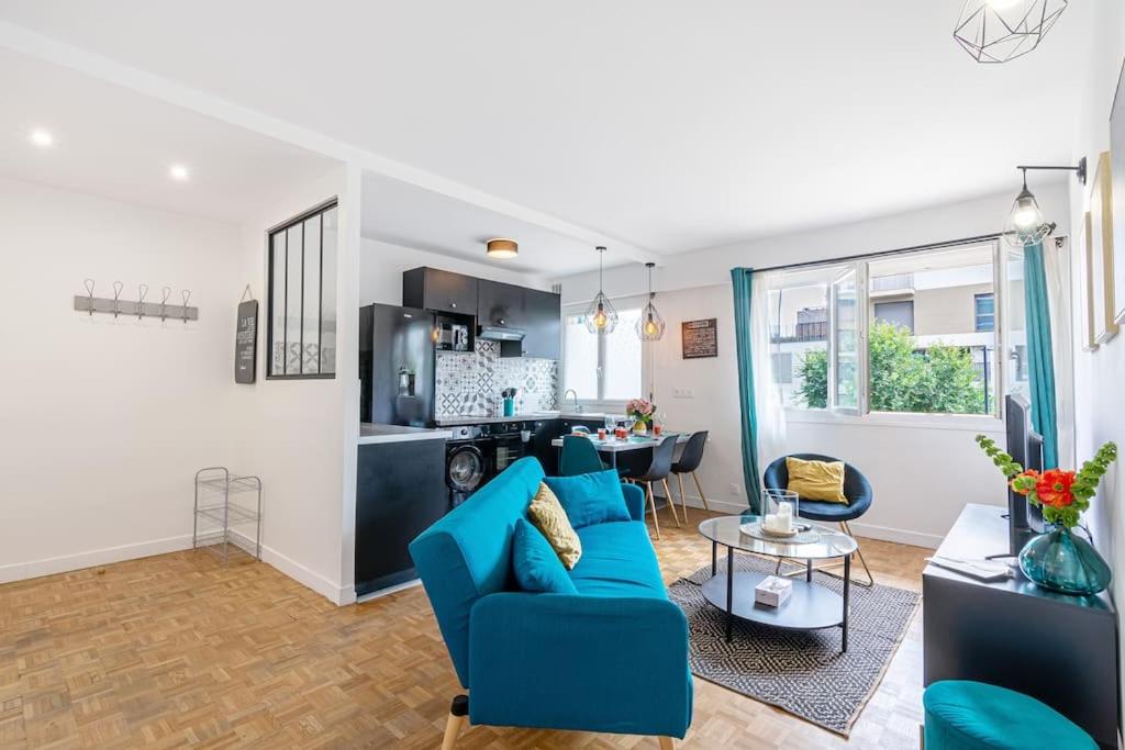 un salon avec un canapé bleu et une cuisine dans l'établissement Appartement de Standing, à Saint-Denis