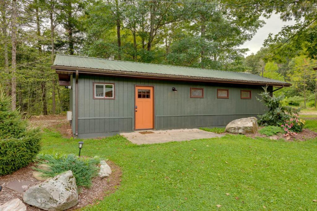 a green building with an orange door in a yard at Pet-Friendly Cabin with Grill in Hillsgrove in Hillsgrove