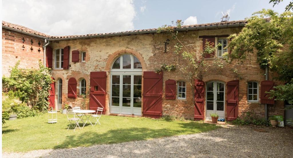 - un vieux bâtiment en briques avec une table dans la cour dans l'établissement Superbe Longère, à Fourquevaux