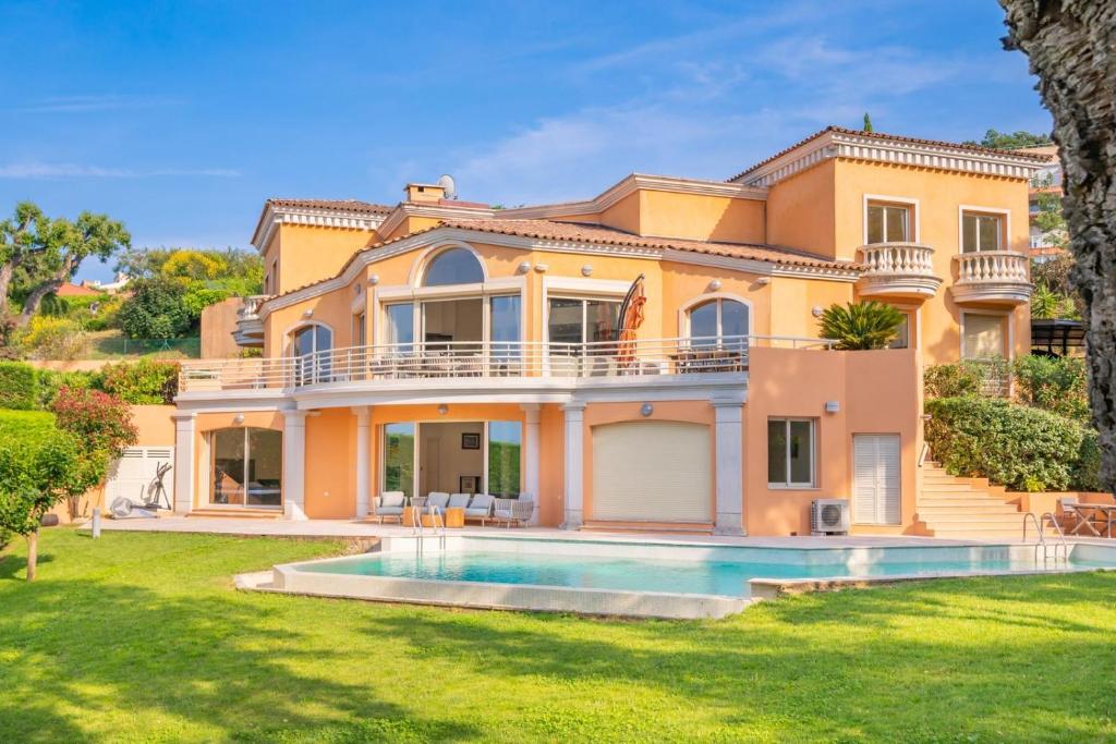 una grande casa gialla con una piscina di fronte di Logement entier villa de luxe avec vue mer a Théoule-sur-Mer
