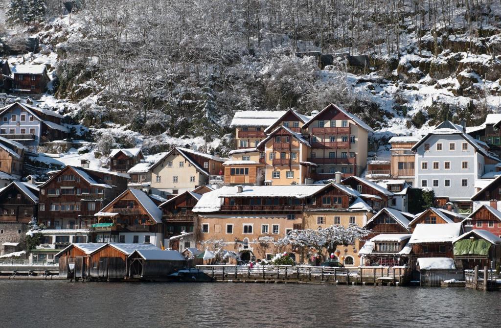 a group of houses with snow on them next to the water at Heritage Hotel Hallstatt in Hallstatt