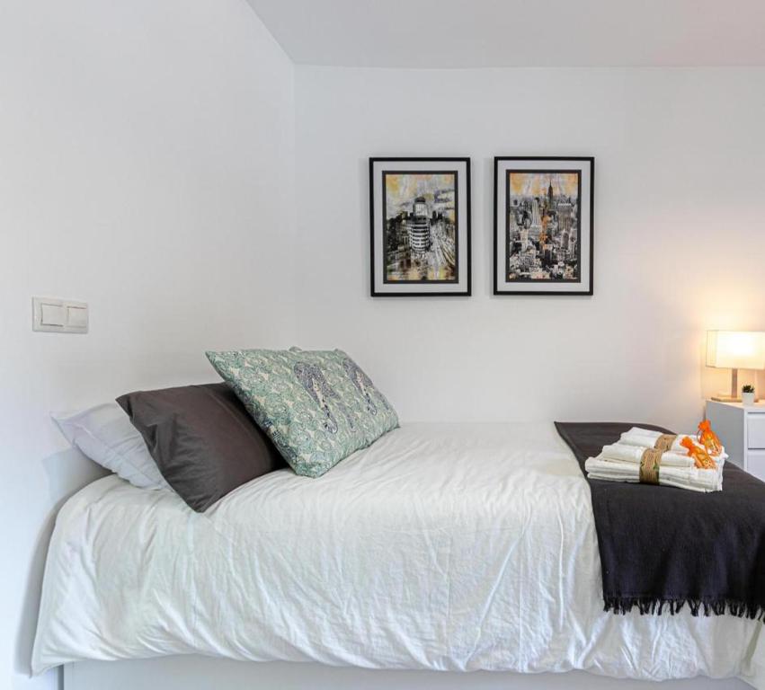 ベナルマデナにあるApartamento Estudio Vacacional Iris, Benalmádenaの白いベッド1台、壁に2枚の写真が飾られたベッドルーム1室