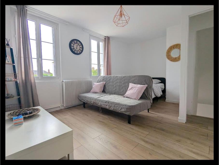 Una sala de estar con un sofá y un reloj en la pared. en maison, en Martot