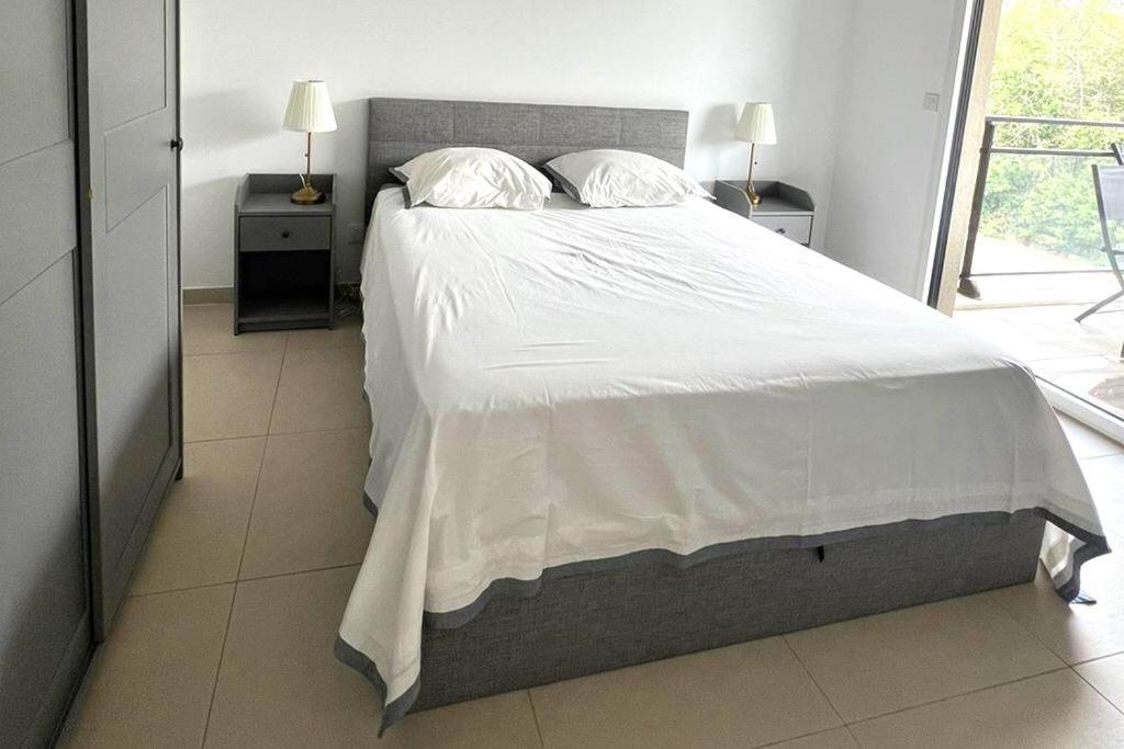 une chambre avec un grand lit avec des draps et des oreillers blancs dans l'établissement Charmant 2 pièces avec belle terrasse à Valbonne, à Valbonne