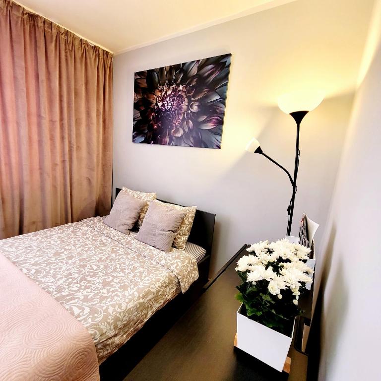 - une chambre avec un lit et un vase de fleurs dans l'établissement Apartament Centrum Warszawa, à Varsovie