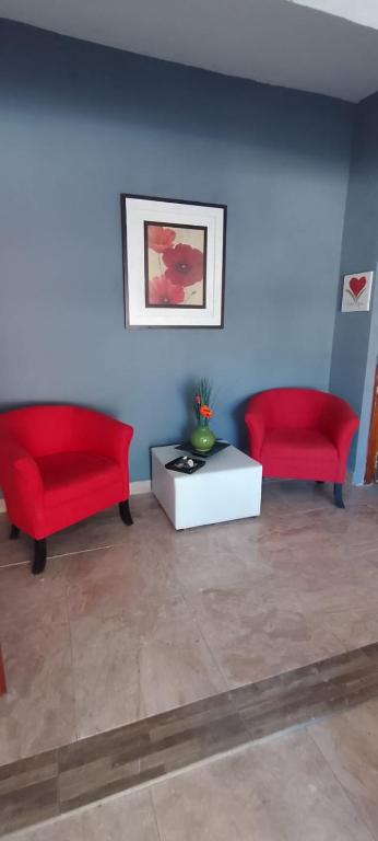 two red chairs and a table in a room at Casitas sc in San Clemente del Tuyú