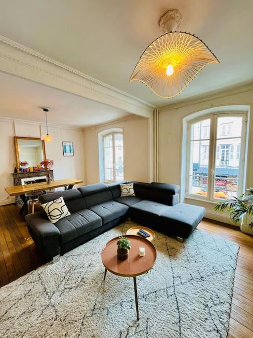 un salon avec un canapé noir et une table dans l'établissement T3 Charmant, à Limoges