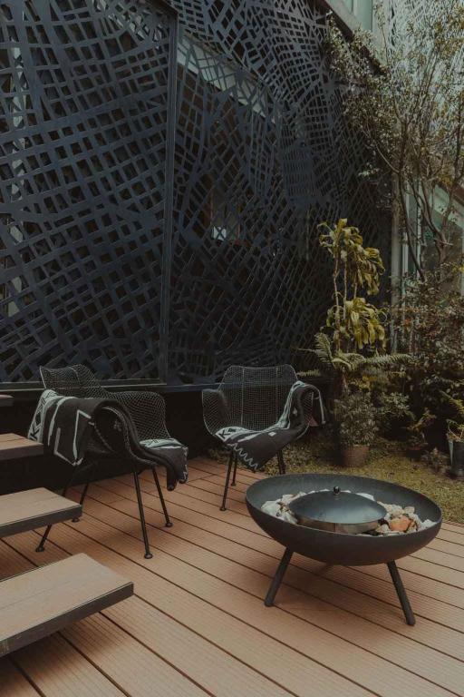 eine Terrasse mit Stühlen und einer Feuerstelle auf einer Holzterrasse in der Unterkunft The Click Clack Hotel Bogotá in Bogotá