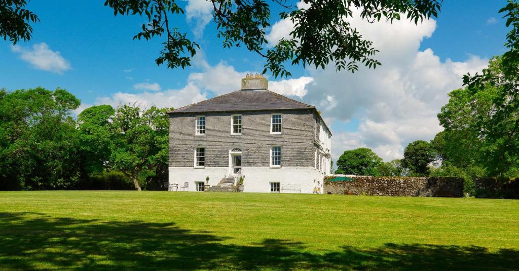 an old house on a grassy field with trees at Kilmahon House, P25A973 in Shanagarry