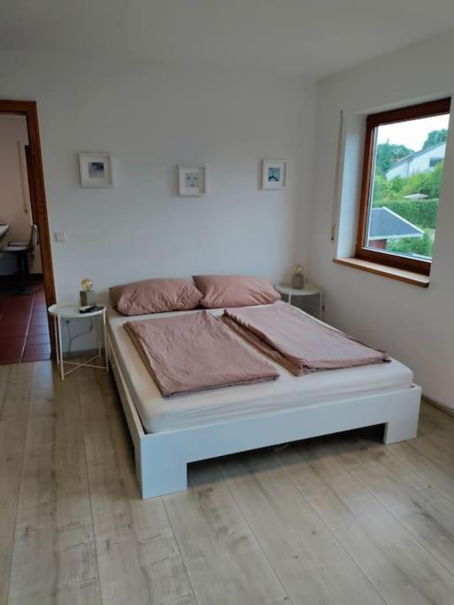 a white bed in a room with a window at Gemütliche Wohnung in Oberteuringen in Oberteuringen