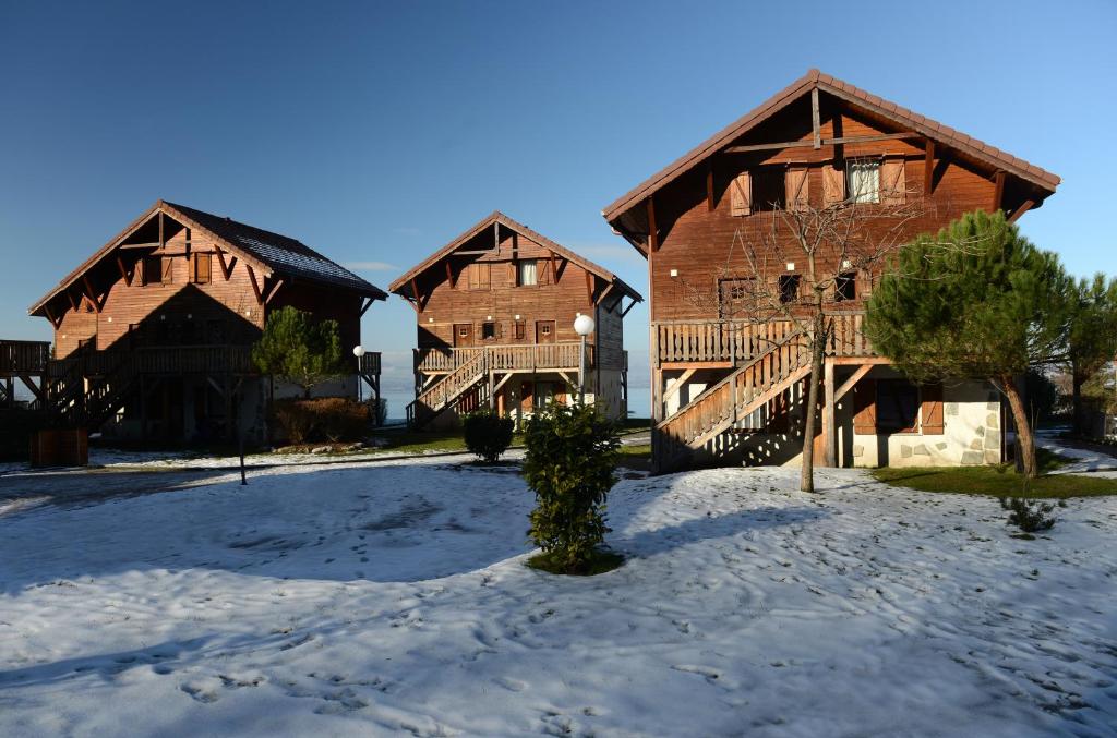 dois grandes edifícios de madeira com neve no chão em Résidence Odalys Les Chalets d'Evian em Évian-les-Bains