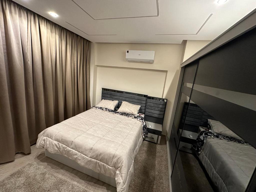 une petite chambre avec un lit et une télévision dans l'établissement Twin House in El patio Zahraa, à Sheikh Zayed