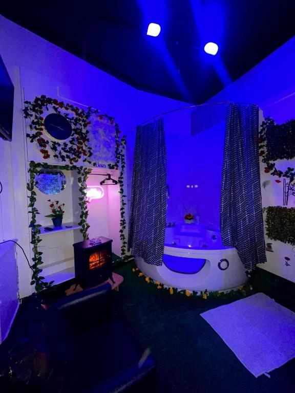- une salle de bains avec baignoire dans une chambre à l'éclairage violet dans l'établissement Love room Paris, à Paris
