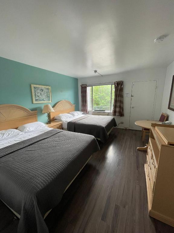 a bedroom with two beds and a table and a window at 6267 Persepolis Inn in Niagara Falls